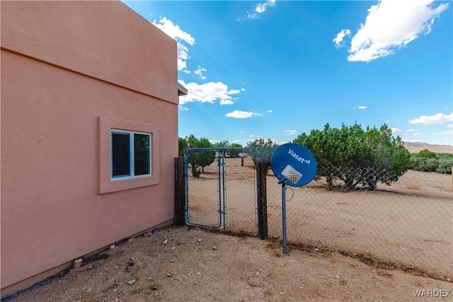 exterior space featuring a gate, fence, and stucco siding