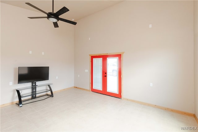 unfurnished living room with french doors, a towering ceiling, and baseboards