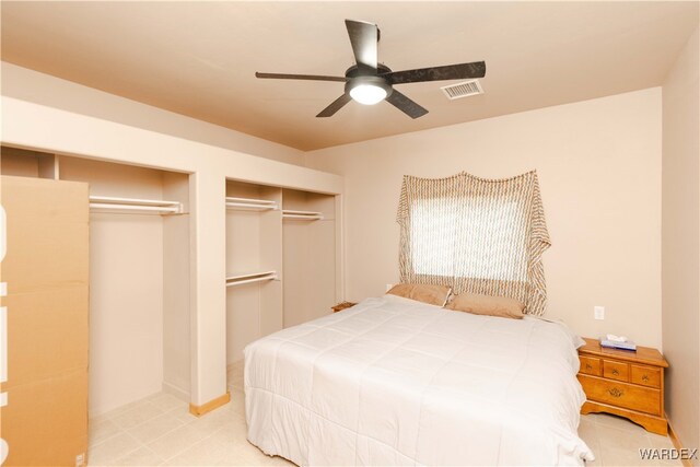 bedroom with a ceiling fan, visible vents, and multiple closets