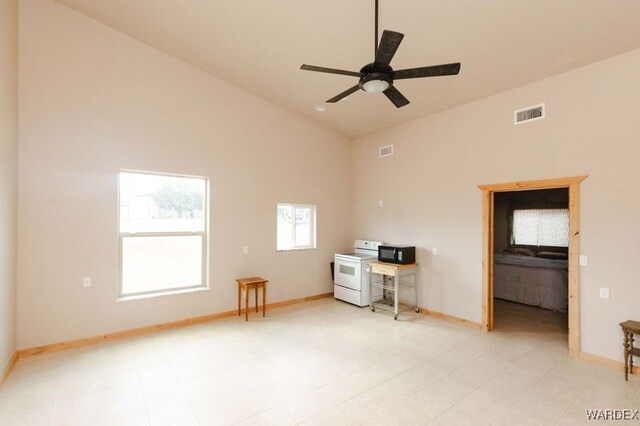 empty room with ceiling fan, high vaulted ceiling, visible vents, and baseboards