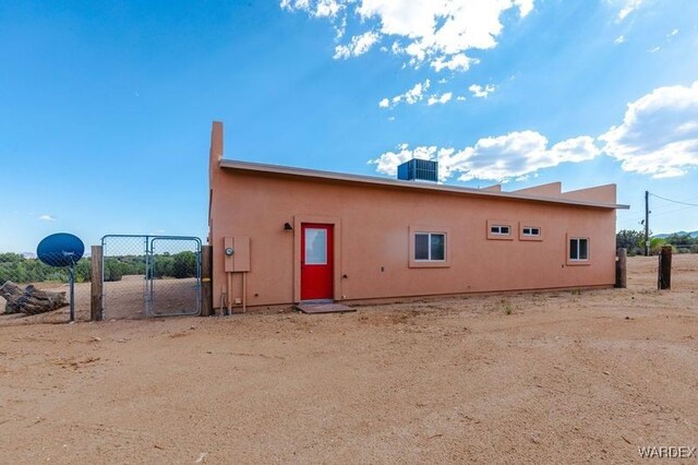 exterior space with a gate, central AC, and stucco siding