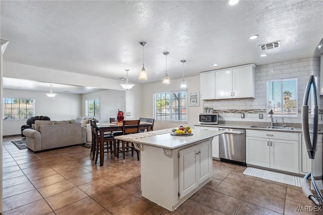 kitchen featuring light countertops, appliances with stainless steel finishes, white cabinets, and a center island