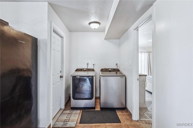 laundry room with laundry area, washer and clothes dryer, and light tile patterned flooring