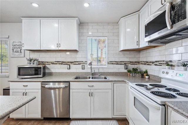 kitchen with white cabinetry, appliances with stainless steel finishes, decorative backsplash, and a sink