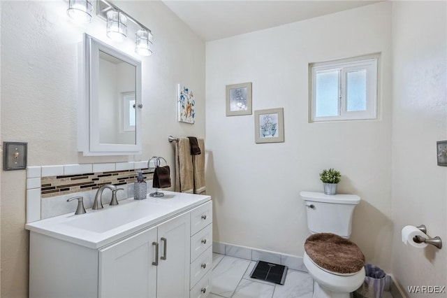 half bath featuring baseboards, decorative backsplash, toilet, marble finish floor, and vanity