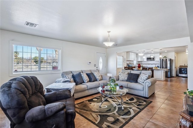 living area featuring light tile patterned flooring, visible vents, and a healthy amount of sunlight