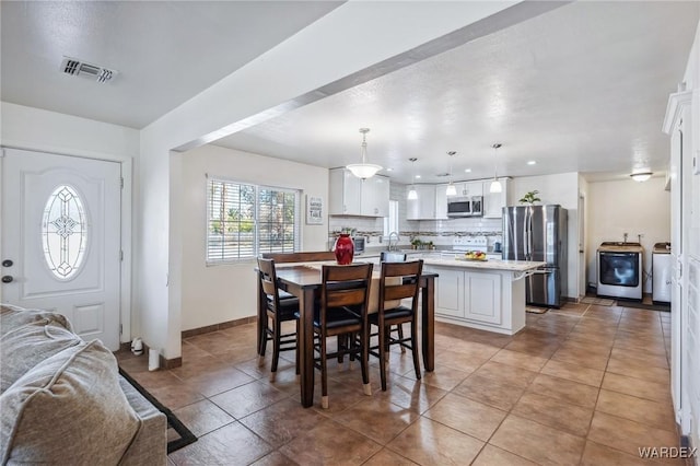 dining space featuring light tile patterned floors, washer / clothes dryer, visible vents, and baseboards