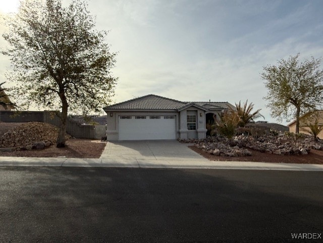 ranch-style house featuring a garage, driveway, and a tile roof