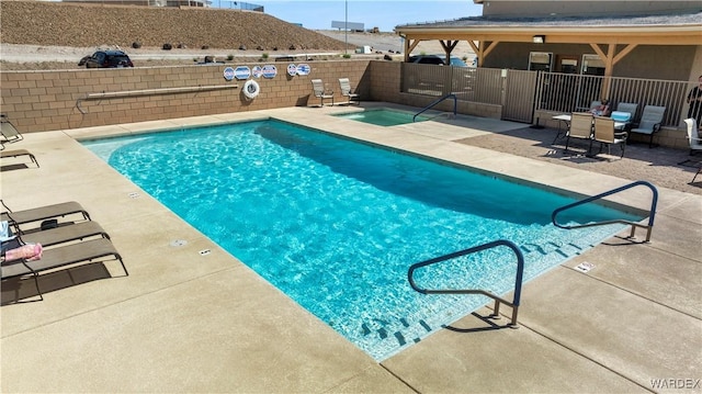 community pool featuring a community hot tub, a patio, and fence