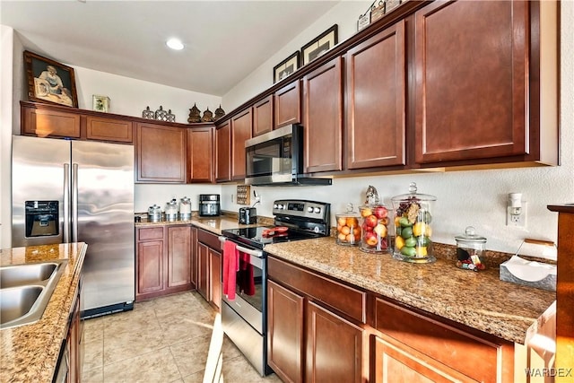 kitchen with light tile patterned floors, appliances with stainless steel finishes, and light stone counters