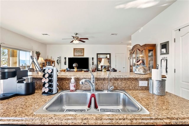 kitchen featuring open floor plan, a sink, visible vents, and a ceiling fan