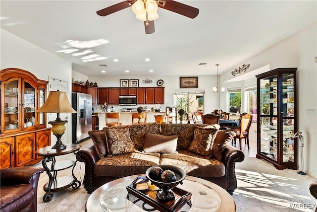 living area with recessed lighting, light carpet, visible vents, and ceiling fan with notable chandelier