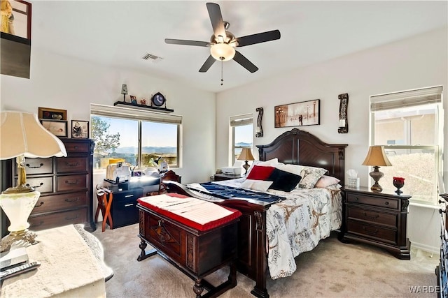 bedroom with a ceiling fan, visible vents, and light colored carpet