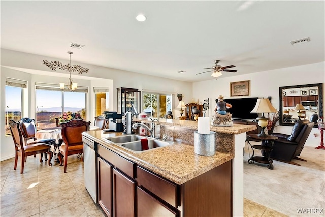 kitchen featuring a kitchen island with sink, a sink, open floor plan, stainless steel dishwasher, and decorative light fixtures