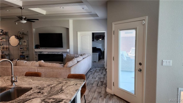 living room with ceiling fan, light wood finished floors, and a fireplace