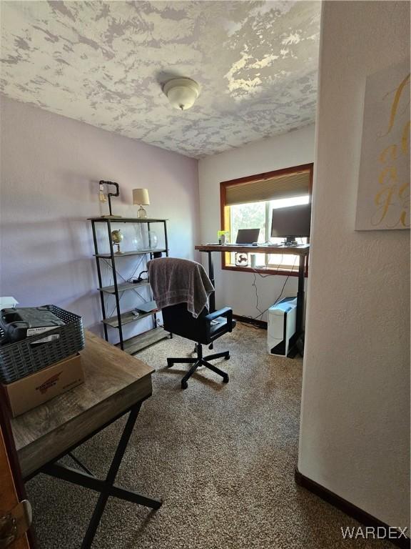 carpeted office space featuring a textured ceiling and baseboards