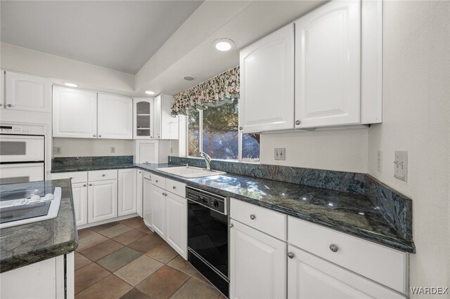 kitchen featuring glass insert cabinets, double oven, white cabinets, a sink, and dishwasher