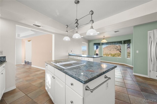 kitchen with electric stovetop, a kitchen island, visible vents, white cabinets, and pendant lighting