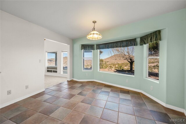 unfurnished dining area featuring an inviting chandelier and baseboards