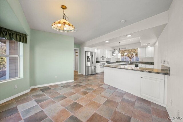 kitchen featuring a peninsula, white cabinetry, stainless steel refrigerator with ice dispenser, and a wealth of natural light