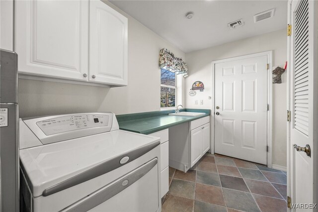 clothes washing area featuring visible vents, cabinet space, a sink, and washer / dryer