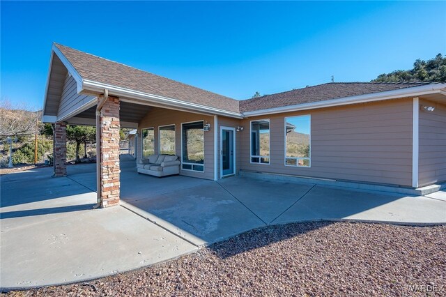 back of property featuring a shingled roof and a patio area