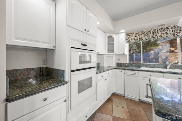 kitchen with glass insert cabinets, dark stone counters, white cabinetry, and double oven