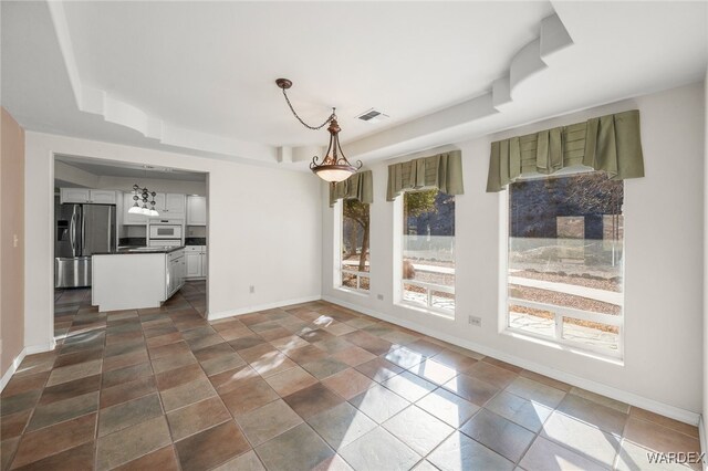 unfurnished dining area with a tray ceiling, visible vents, and baseboards