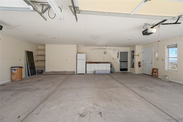 garage featuring baseboards, freestanding refrigerator, and a garage door opener