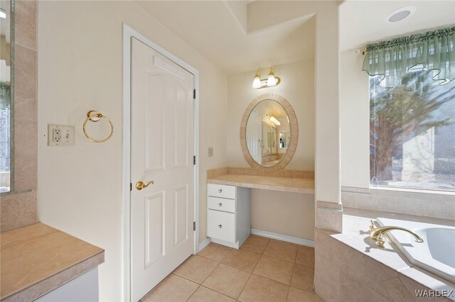 bathroom with a garden tub, tile patterned flooring, and vanity