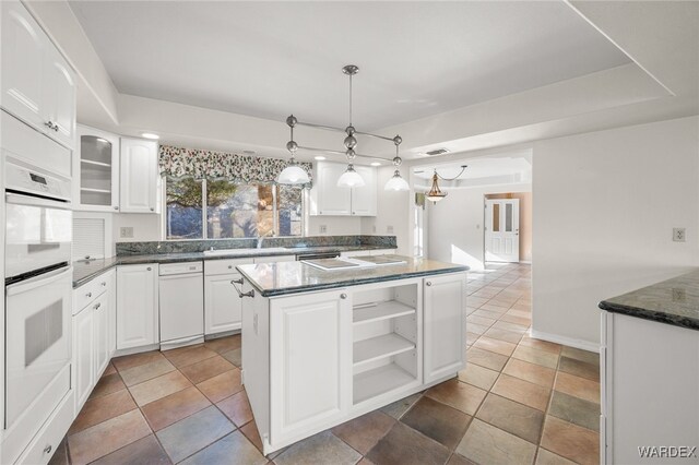 kitchen with white double oven, white cabinets, open shelves, dark countertops, and glass insert cabinets