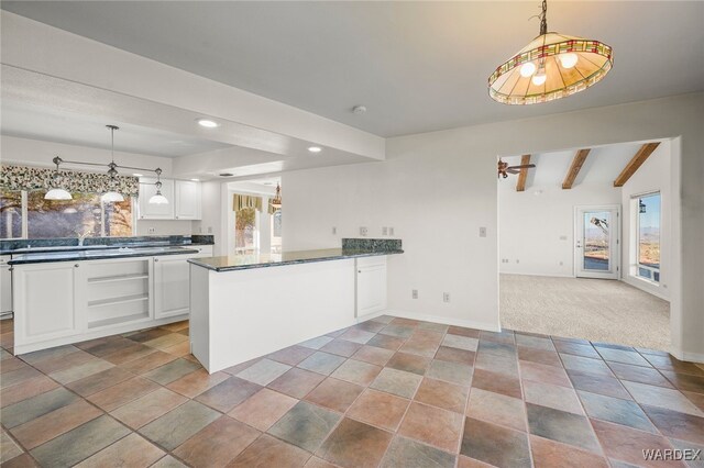 kitchen with light colored carpet, white cabinetry, open floor plan, beamed ceiling, and dark countertops