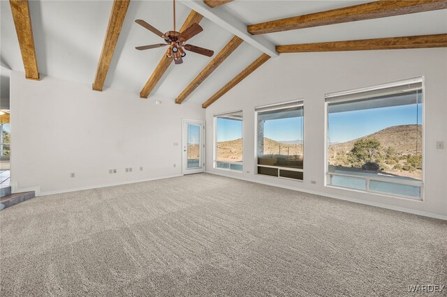 carpeted empty room with baseboards, a ceiling fan, beamed ceiling, high vaulted ceiling, and a mountain view