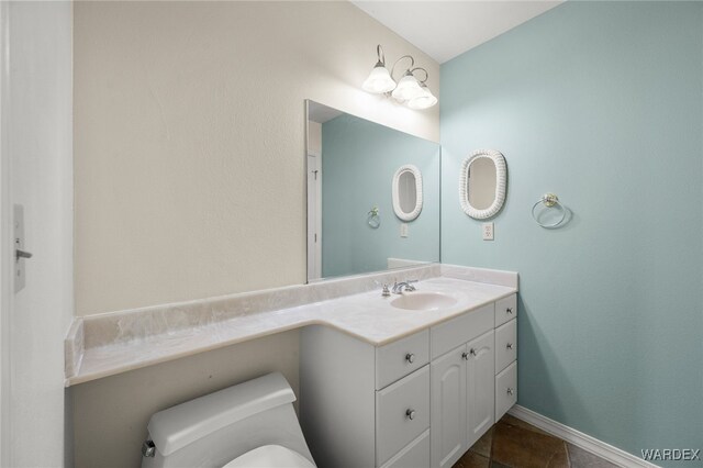 half bath with toilet, vanity, and baseboards