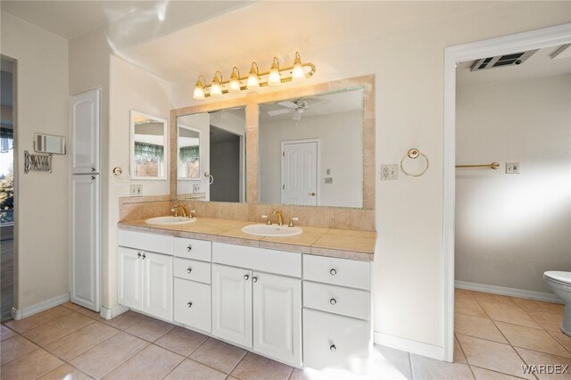 bathroom featuring tile patterned floors, a sink, toilet, and double vanity