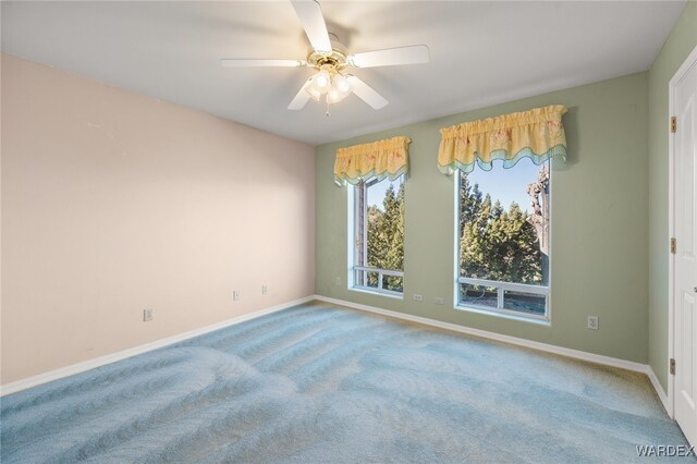 carpeted spare room featuring a ceiling fan and baseboards