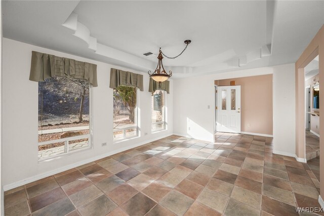 unfurnished room with a tray ceiling, visible vents, and baseboards