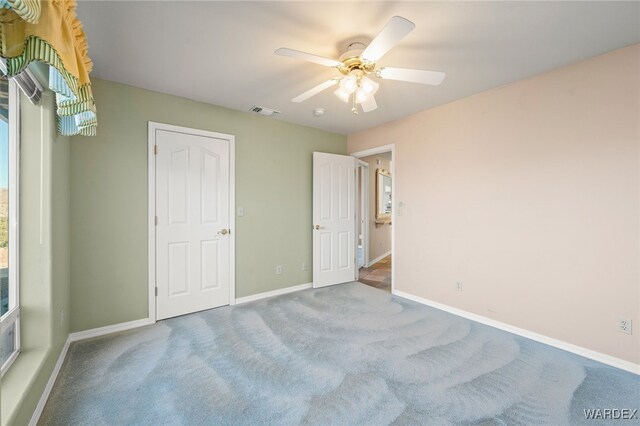 unfurnished bedroom with carpet floors, a ceiling fan, visible vents, and baseboards