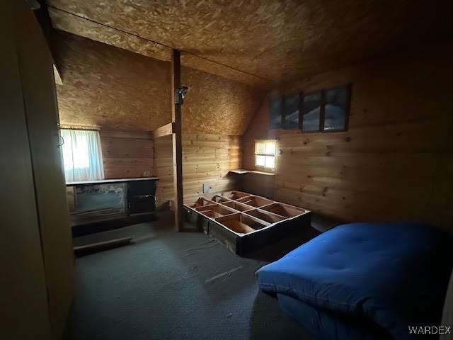 carpeted bedroom with vaulted ceiling and wood walls