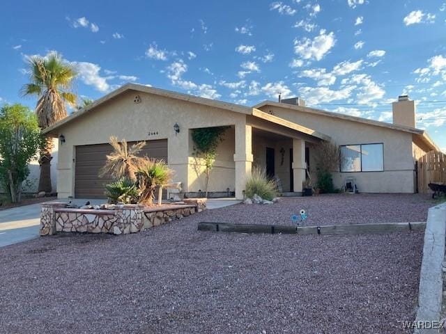 view of front of house with a garage, a chimney, and stucco siding