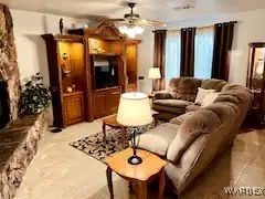 living room featuring a large fireplace and ceiling fan