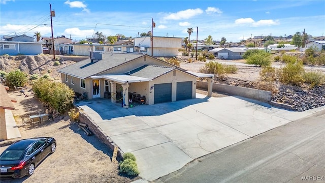 ranch-style house with a residential view, concrete driveway, central AC, and an attached garage