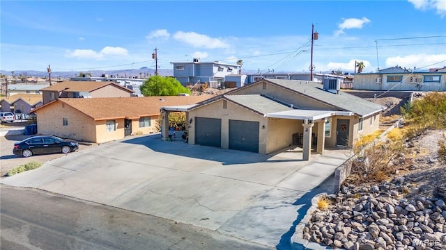 ranch-style house with a garage, concrete driveway, a residential view, and stucco siding