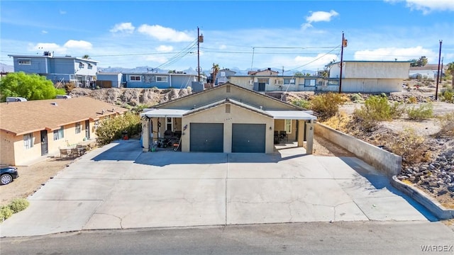 ranch-style house with driveway, an attached garage, a residential view, and stucco siding