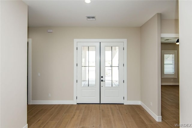 entrance foyer with french doors, light wood finished floors, visible vents, and baseboards