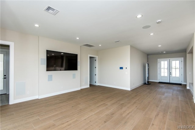 unfurnished living room featuring visible vents, baseboards, french doors, light wood-style floors, and recessed lighting