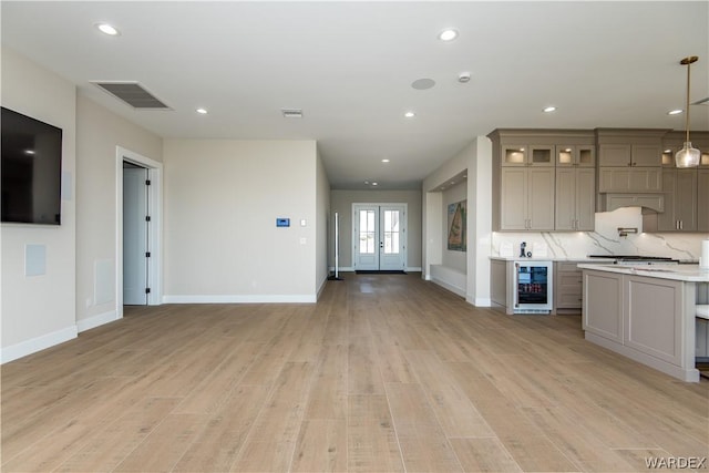 kitchen with beverage cooler, visible vents, light countertops, glass insert cabinets, and pendant lighting