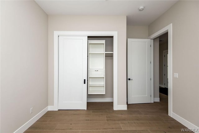 unfurnished bedroom featuring a closet, baseboards, and wood finished floors