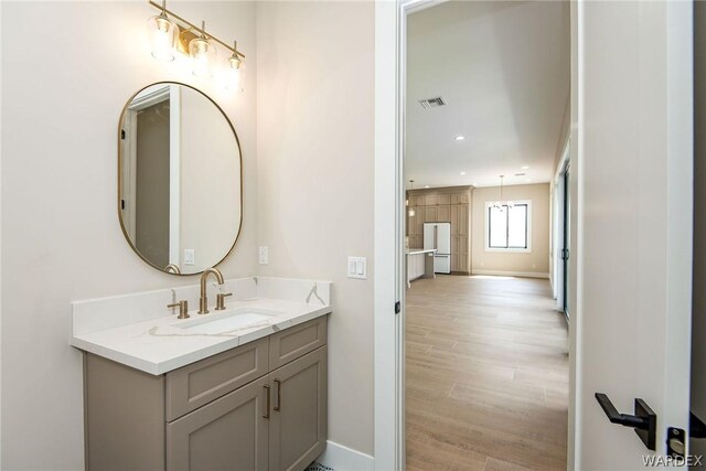 bathroom featuring baseboards, visible vents, wood finished floors, vanity, and recessed lighting