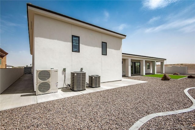 back of house with ac unit, stucco siding, a fenced backyard, and central air condition unit